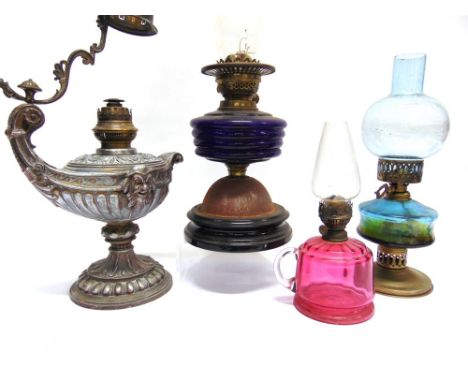 AN EARLY 20TH CENTURY OIL LAMP,  decorated with masks and foliate motifs (lacking shade), and three further oil lamps with co