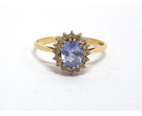 A SAPPHIRE AND DIAMOND 9 CARAT GOLD CLUSTER RING the oval cut stone enclosed by sixteen brilliant cuts totalling approximatel