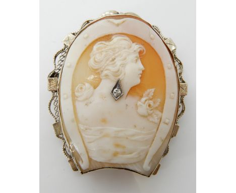 A 14ct white gold horseshoe shaped brooch set with a shell cameo, carved with a horseshoe and a maiden, also set with a diamo