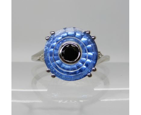 A 9ct white gold 'Torus cut' blue topaz, black spinel, and diamond ring. The Torus cut was created by Glenn Lehrer a world re