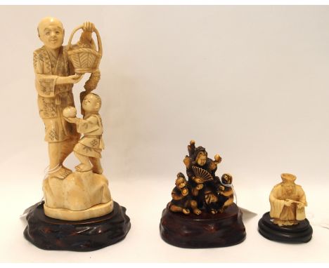 A Japanese ivory carving of a man carrying a basket, with a child at his feet, 19.5cm high, on wood stand, a netsuke carved a