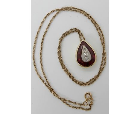 A 9ct gold pear shaped pendant set with a red gem, with white metal inset panel set with three diamonds with an estimated app