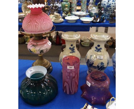 A Victorian oil lamp, a milk glass cranberry shade, a cylindrical cranberry shade with iris design and a green and white glas