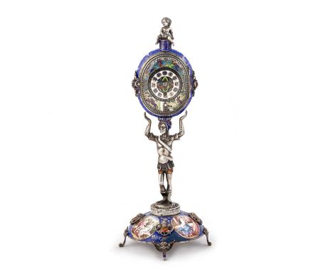 AN AUSTRIAN SILVER AND ENAMEL FIGURAL STANDING CLOCK  Vienna, c.1890, on a domed base and with winged putto head feet, the ba