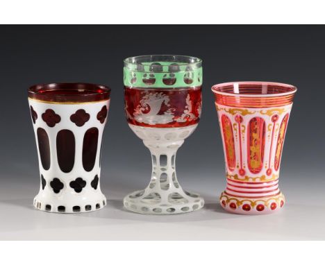 2 Becher und 1 Kelchglas. Um 1850.                         1x Fußbecher aus rubinrotem, weiß überfangenem Glas mit Linsen- un
