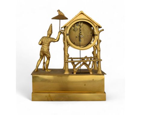 A French Empire style gilt mantel clock in Oriental taste, with the figure of a man holding a rifle and parasol with a parrot