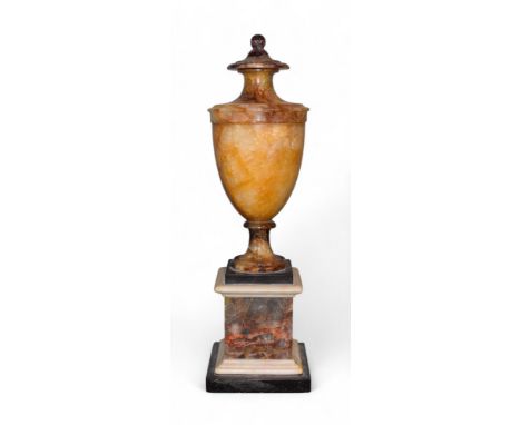 A Blue John urn Of yellowish hue. With attached finial lid. On a black slate base, surmounted on a Blue John, white marble &n