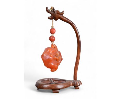 Chinese 19th Century Carnelian or orange jade pendant on a wood stand Property of a gentleman From the collection of Peter Ro