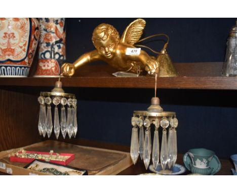 An early 20th century ceiling light in the form of a cherub holding two glass lustre droplet pendants.