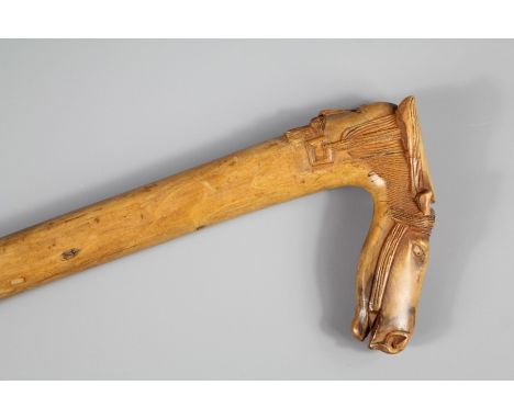 A Dense Fruit Wood Carved Walking Stick. The grip carved with a horse head and a carved face to the reverse, approx 88 cms, m