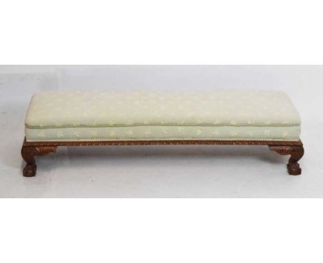 Early 20th Century carved fender stool with leaf patterned upholstery against a light green ground, on ball and claw supports