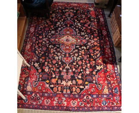 A Persian design carpet with stylised floral decoration on a dark blue ground, deeply bordered