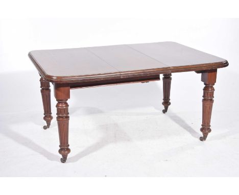 A Victorian mahogany extending dining table The rectangular moulded top with rounded corners and a single leaf raised upon ri