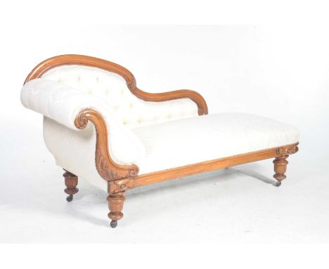 A Victorian mahogany framed chaise lounge With an arched padded and button back and a conforming padded scrolling end above a