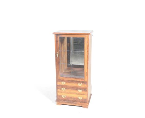 The hardwood display cabinet by Mike Brown and MullerHaving a single leaded glazed door enclosing two glass shelves above thr