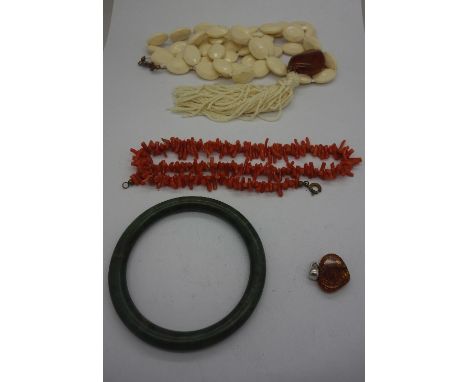 A jade bangle, a coral twig necklace, an amber pendant and a necklace