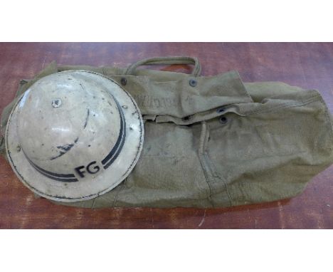 A World War II kit bag and a helmet, marked FG