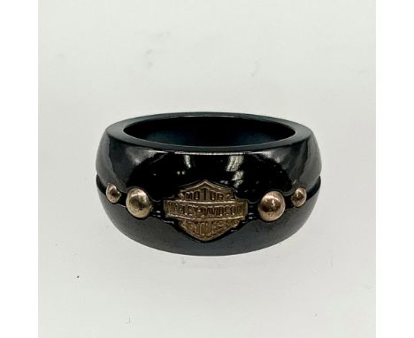 Black titanium band with silver tone Harley Davidson logo and studs and a thin blue channel stripe around the middle. Titaniu