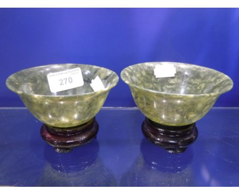 A PAIR OF CHINESE GREEN "JADE" BOWLS, each 10 cm dia. on wooden stands