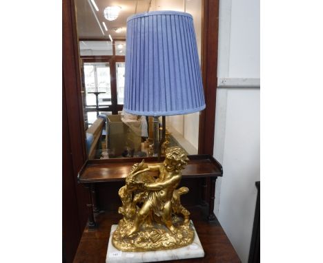 A TABLE LAMP, DECORATED WITH A GILT STUDY OF A CHILD WITH A GOAT, on a white marble base, with a blue pleated shade, 71 cm hi