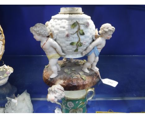 A CONTINENTAL PORCELAIN OIL LAMP BASE in the form of a basket held by three cherubs