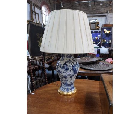 A TABLE LAMP IN THE FORM OF AN ORIENTAL BLUE AND WHITE VASE, with a crackle glaze, on a gilt base, with pleated shade, 68 cm 