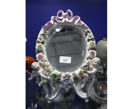 A CONTINENTAL CERAMIC FRAMED DRESSING TABLE MIRROR, 27 cm high with floral and angel figure decoration 