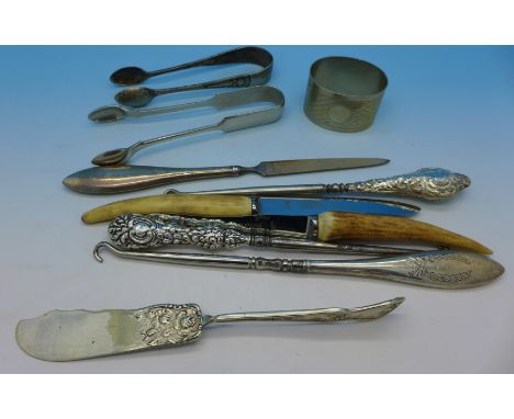 Three silver handled button hooks and a silver handled file, two sugar bows, a napkin ring, etc.