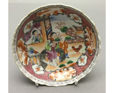 An 18th century Chinese porcelain saucer
Decorated with figures in a fenced garden within landscape vignettes, red painted ma