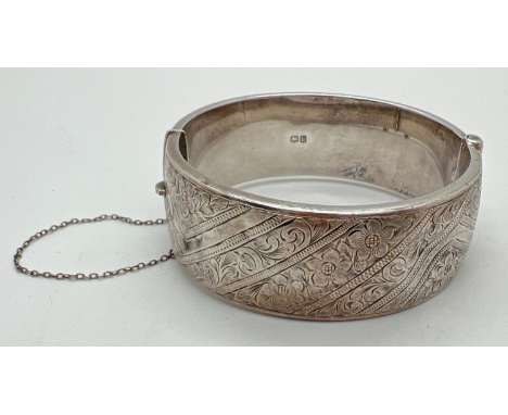 A vintage silver bangle with half floral engraved detail and safety chain (a/f). Full hallmarks to inside for Chester 1961. A