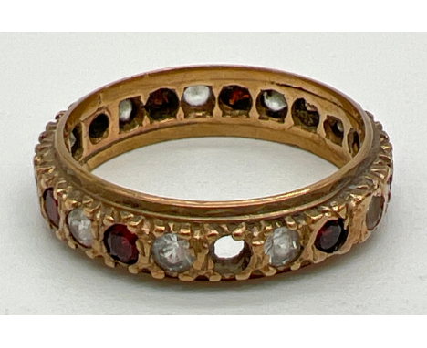 A vintage 9ct gold full eternity ring set with round cut garnets and clear stones (one garnet mising). Full hallmarks to insi