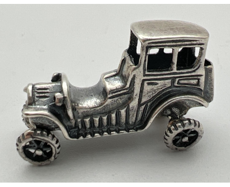 A small 925 silver model of a vintage veteran car with moving wheels. Stamped 925 to underside. Approx. 2cm tall x 3.25cm lon