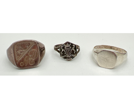 3 silver signet rings. A plain square ring with empty cartouche, a small ring with shield detail and coin edge pattern to ban