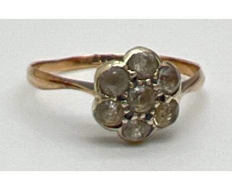 A vintage 9ct gold Art Deco flower design dress ring set with 7 round cut white sapphires. Gold mark to inside of band. Size 