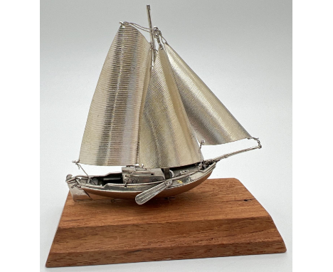 A vintage silver model of a sailing boat mounted on a wooden plinth. Very well detailed with matte finish sails and twisted d