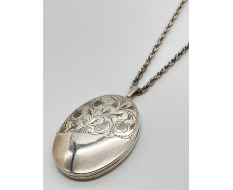 A large vintage silver oval shaped locket with half engraved detail of scroll &amp; foliate design. On a 24" sterling silver 