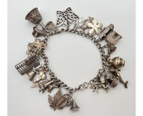 A vintage white metal charm bracelet with 26 assorted silver &amp; white metal charms. Charms to include wishing well with pi