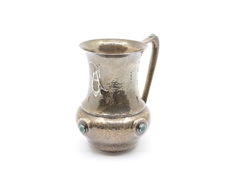 An Arts &amp; Crafts silver large mug in the manner of Liberty, the baluster hammered body with flared rim above chased monog