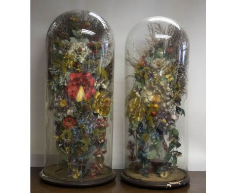 A pair of Victorian large glass domes containing Ganutell style and dyed ostrich feathers contained in ruby flash cut glass b