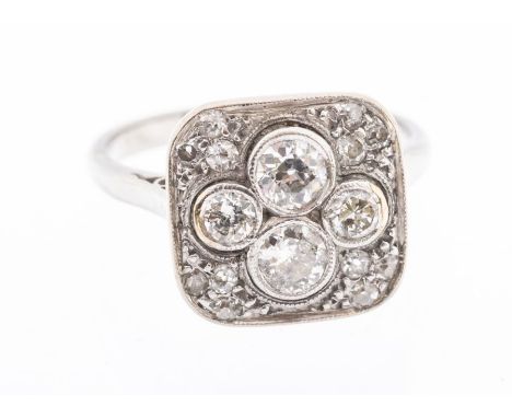 An Art Deco circa 1930's diamond platinum and gold ring, comprising a cushion setting, the centre rub over set with a quatref