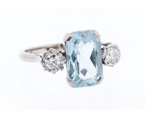 An aquamarine and diamond platinum three-stone 18ct and platinum ring, comprising a rectangular mixed cut aquamarine claw set