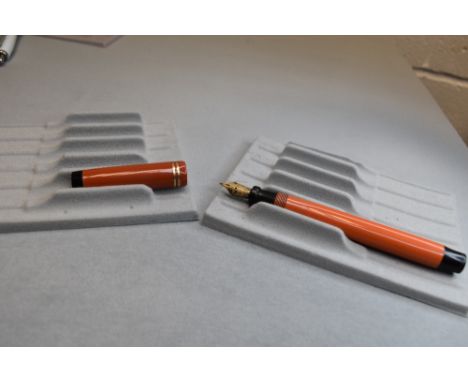 A Parker Duofold Lucky Curve button fill fountain pen in orange with two narrow bands to the cap having Parker Duofold nib. A