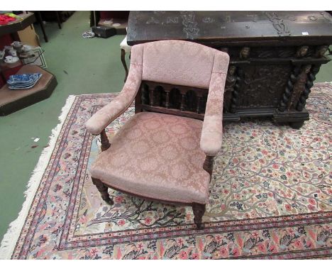 In the manner of Shoolbred a Victorian walnut armchair on turned supports and legs with ceramic castors