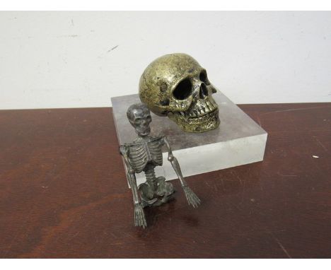 A cast metal skull with articulated jaw and skeleton with perspex block 