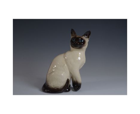 A Royal Doulton seated Siamese cat figurine, model D127. This finely crafted ceramic sculpture features a lifelike depiction 