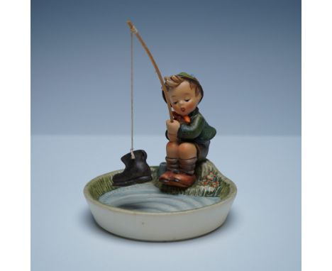 This charming figure features a young boy seated at the edge of a pond, engrossed in fishing. His expression of surprise and 