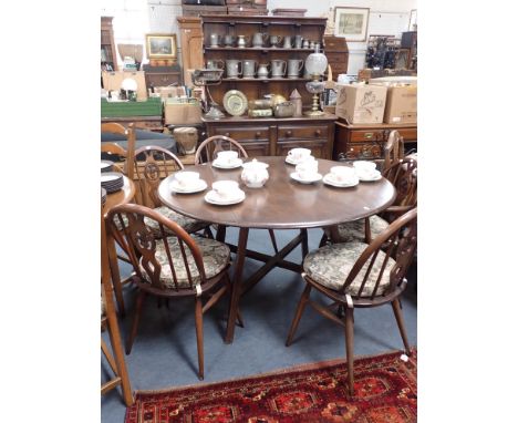 ERCOL: A DARK ELM AND BEECH DINING SUITE comprising drop-leaf table 112 x 125cm (open), five Prince of Wales feathers back Wn