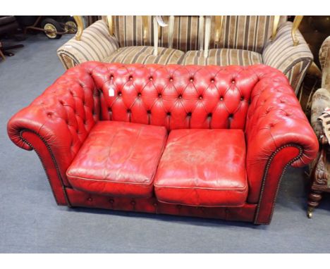 A SMALL CHESTERFIELD SOFA, IN PATINATED RED LEATHER buttoned and studded, with bun feet 153cm wide