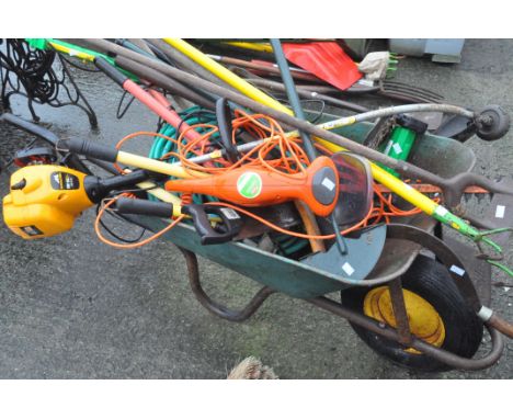 A large collection of gardening tools and a wheelbarrow