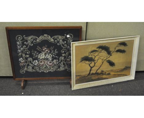 An oak framed fire screen with a floral needlework panel set to centre, 75cm high x 18cm wide; together with a landscape prin